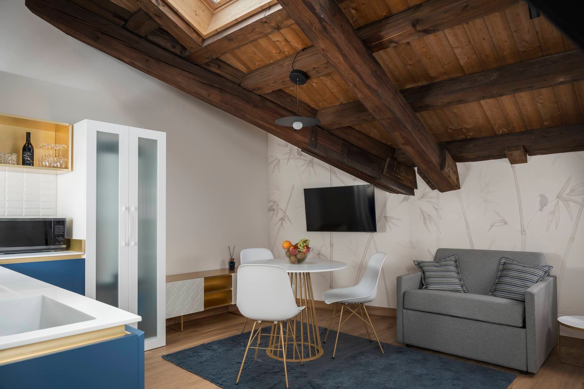 Detail of the living area with armchair and dining table in the Standard Apartment with beamed ceiling