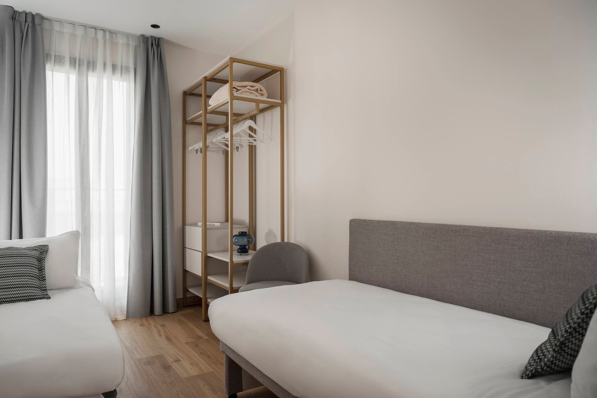 Bedroom detail with double bed and extra bed, open wardrobe in the Classic Apartment