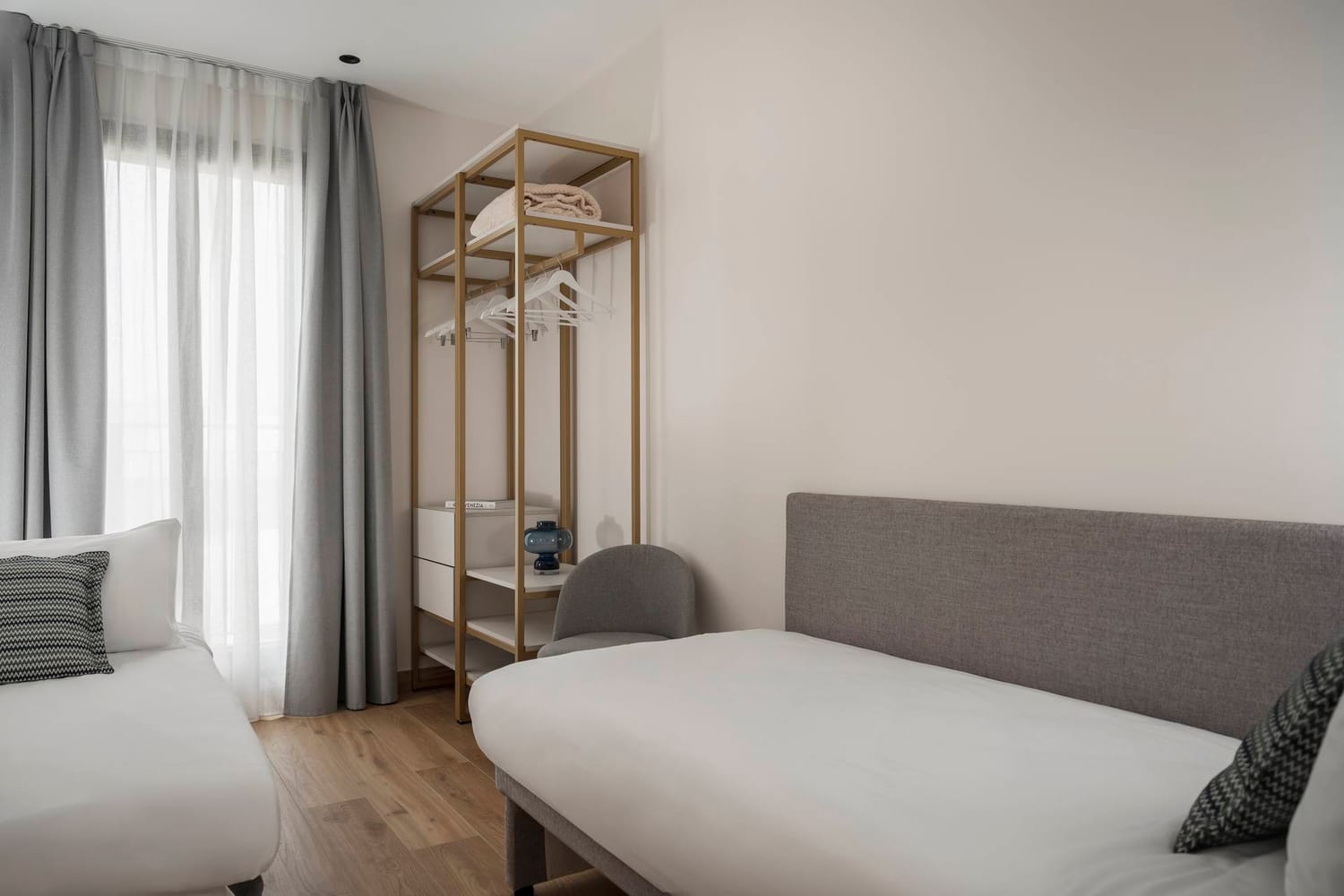 Bedroom detail with double bed and extra bed, open wardrobe in the Classic Apartment
