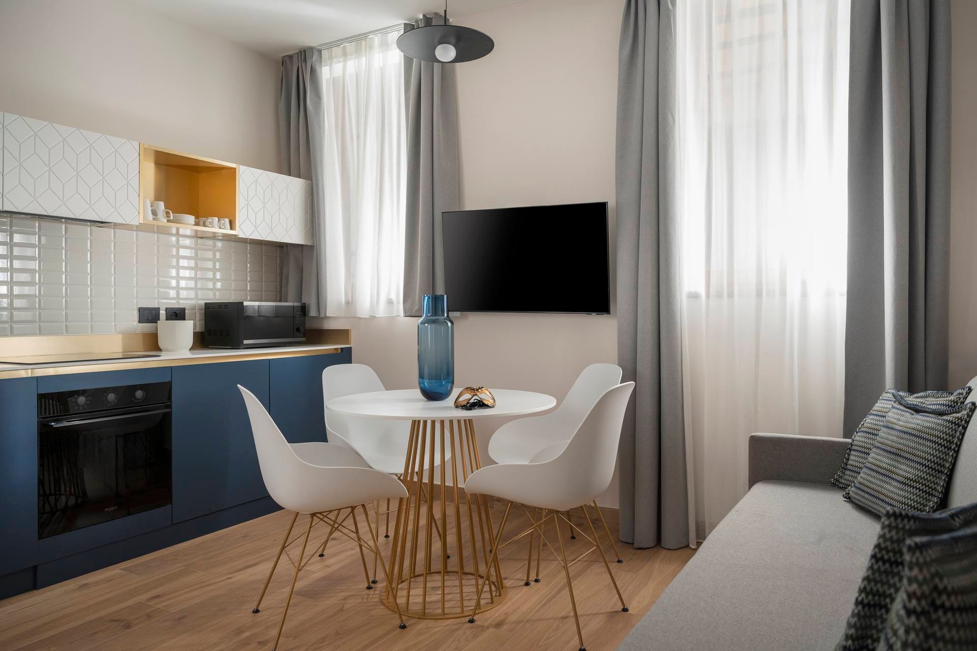 Equipped kitchen with dining table, TV, and sofa in the Standard Apartment